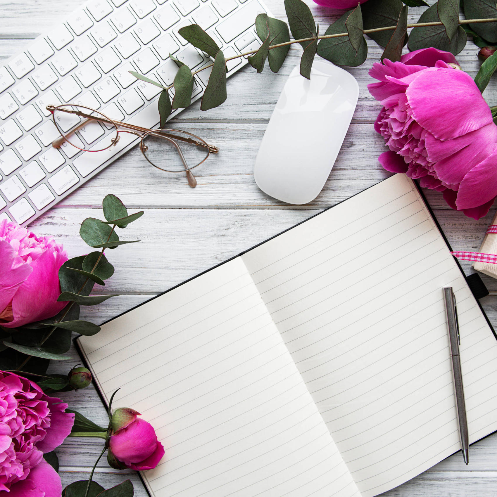 Notebook journal on desk with peony flowers and pen