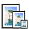 Palm tree set against blue sky and reflecting in clear turquoise water. Fine art print in a black frame with a white mount. Different sizes, smallest at the front.