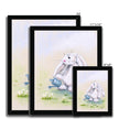 White fluffy rabbit watering the daisies with a little blue watering can, nursery art prints in a black frame. Different sizes